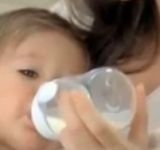 Ребенок пьет из бутылочки детскую смесь